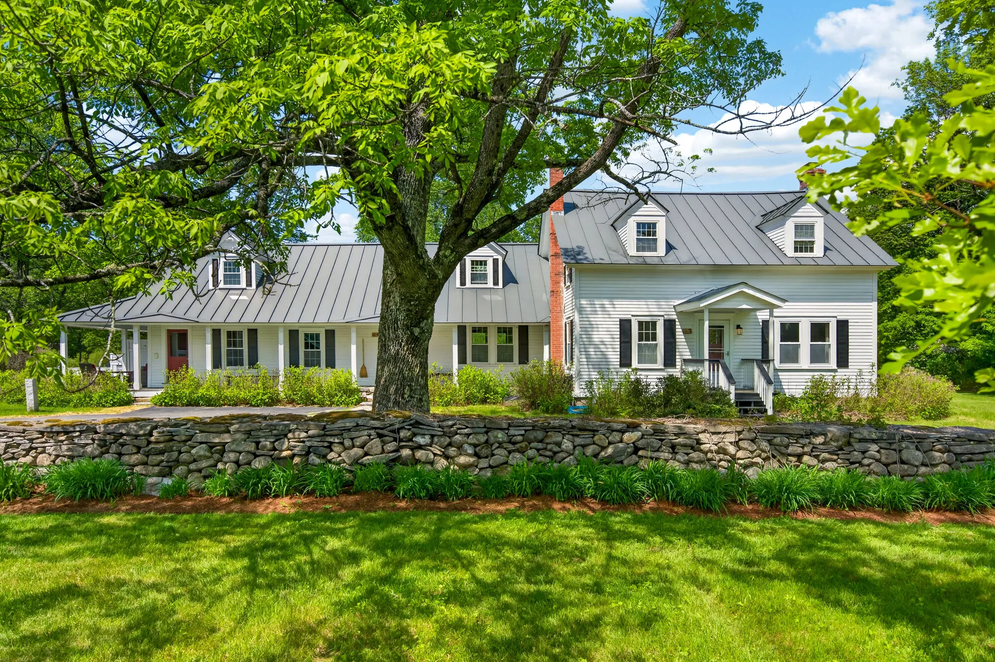 White Vermont farmhouse behind a stone wall